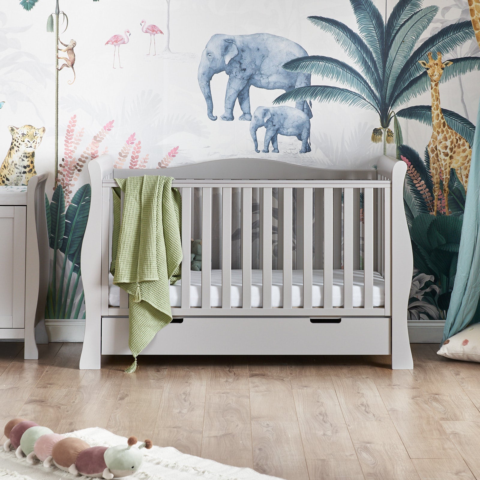 Sleigh cot bed has curved open sides, with rails, back panel has curve in the middle, front rail is topped with teething rail. Under drawer included with open cut out handles.